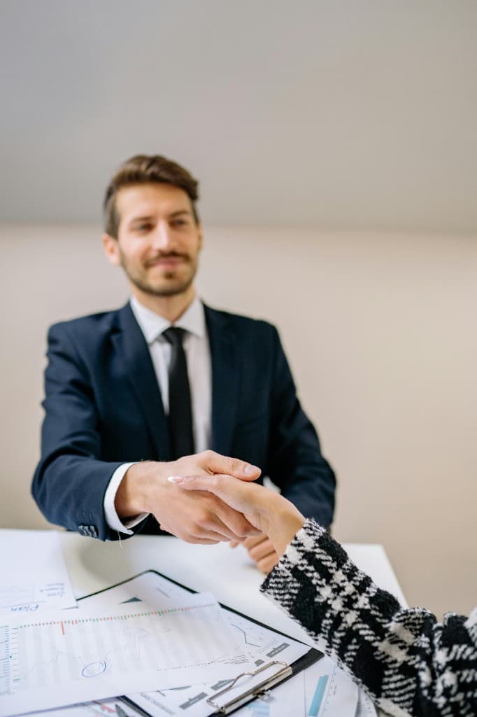 Professional handshake across a desk after completing hiring paperwork