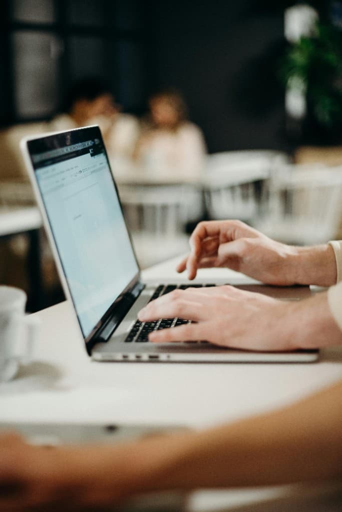 Person typing on a laptop while organizing job search materials at a desk
